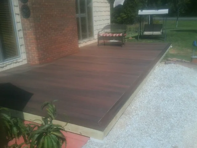 Freshly stained wood deck built against a brick home in Stacy