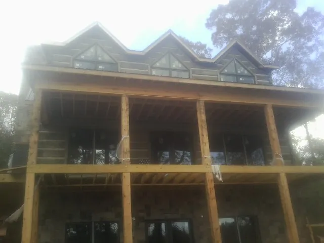 Dormers and porch framing on a large log home under construction — Roof Coating work by our crew in Stacy