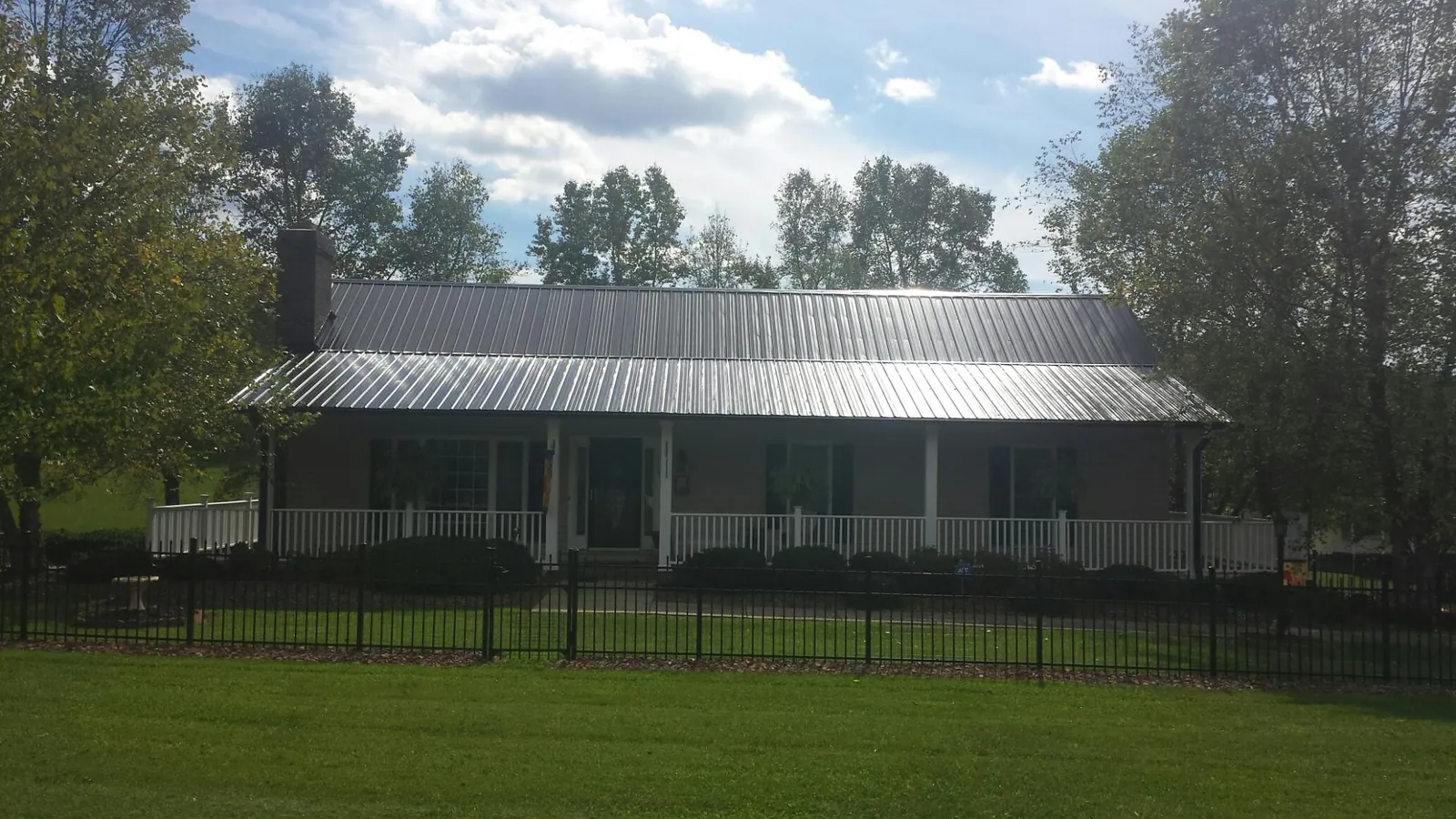 Gray metal roof on a brick ranch with a full width front porch — Gutter Guard Installation work by our crew in Stacy