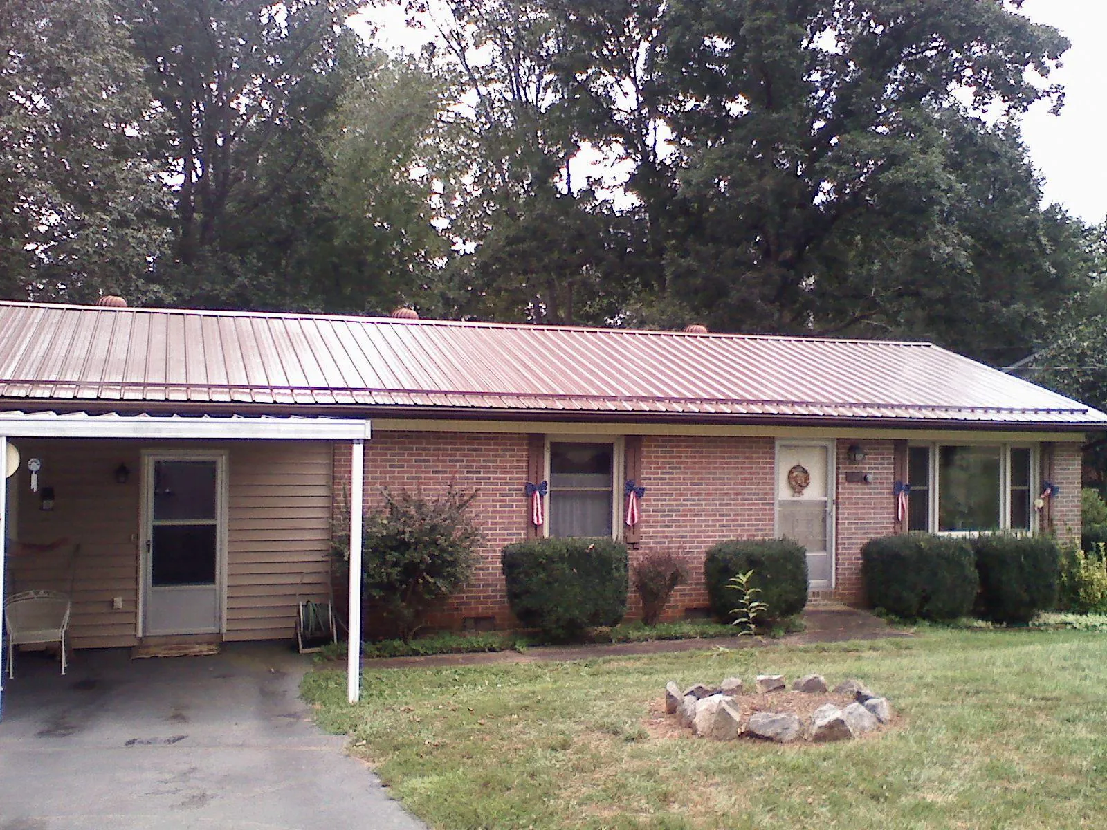 Bronze metal roof and carport on a brick ranch home — Roof Repair work by our crew in Stacy